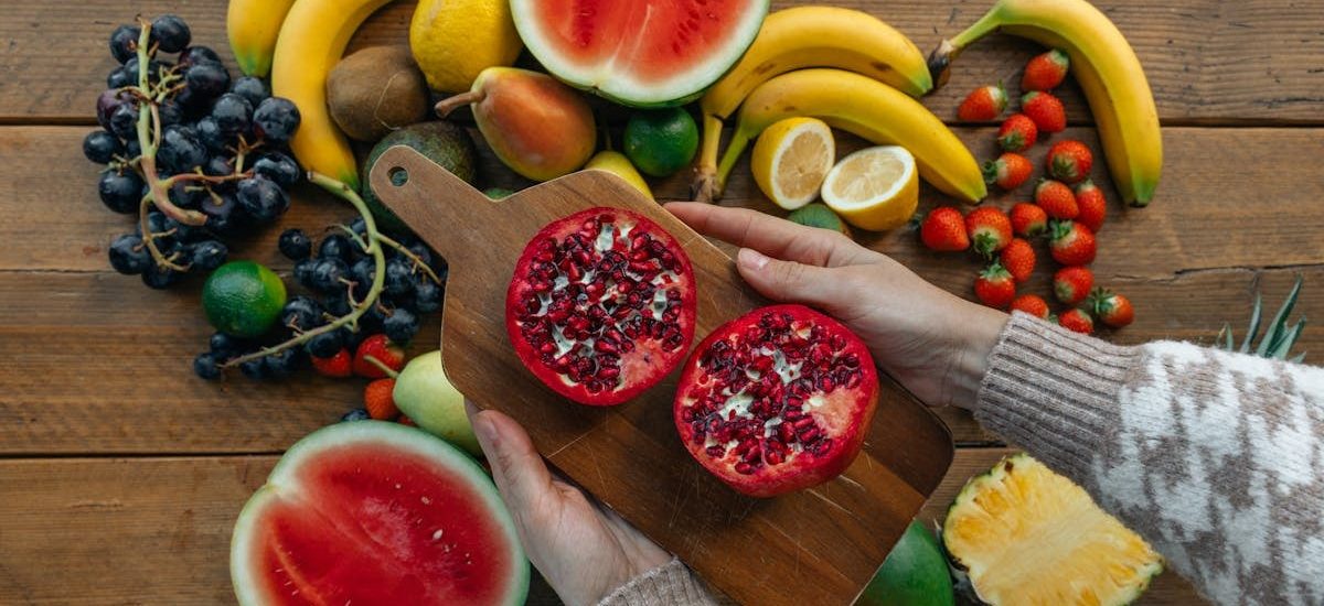 Vibrant fruits including pomegranates, bananas, and watermelon on a rustic wooden table.