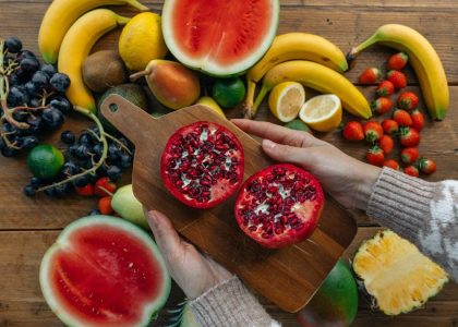Vibrant fruits including pomegranates, bananas, and watermelon on a rustic wooden table.